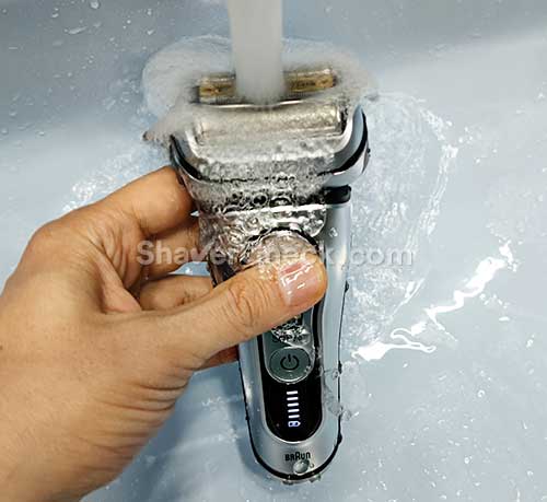 Rinsing the shaving head with warm water.
