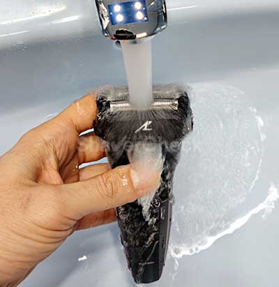 Rinsing the shaving head with warm tap water.